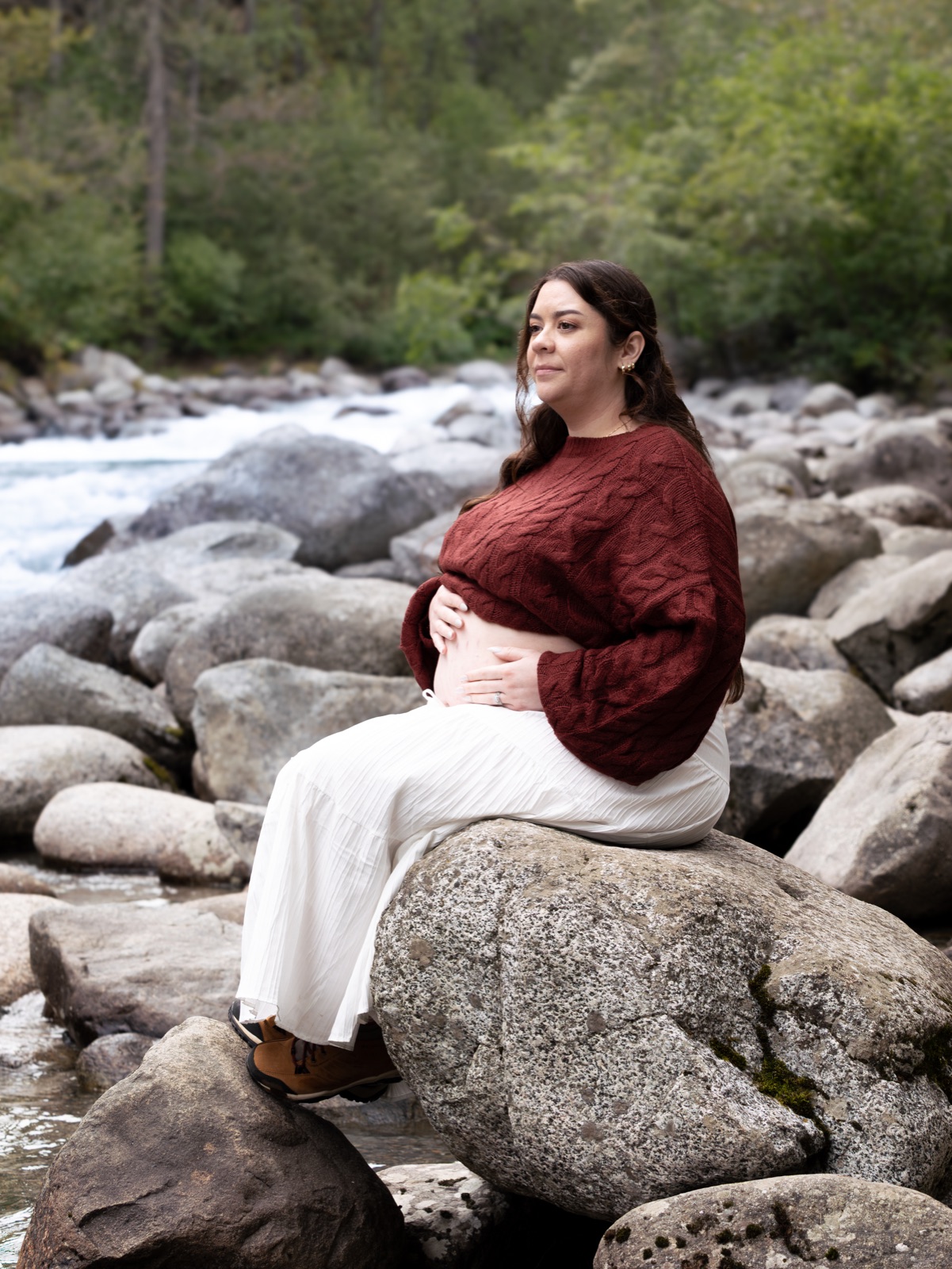 An expecting mother seated beside a stream