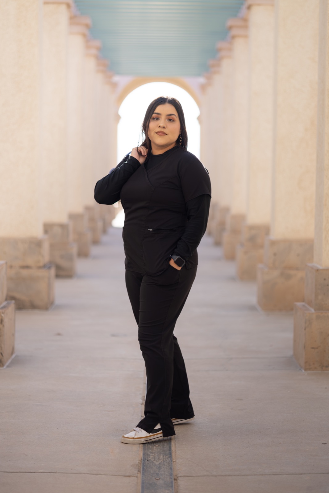 A graduate standing beneath courtyard arches
