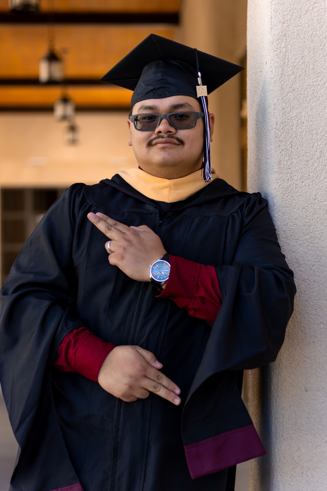 A graduate in a cap and gown with a red watch