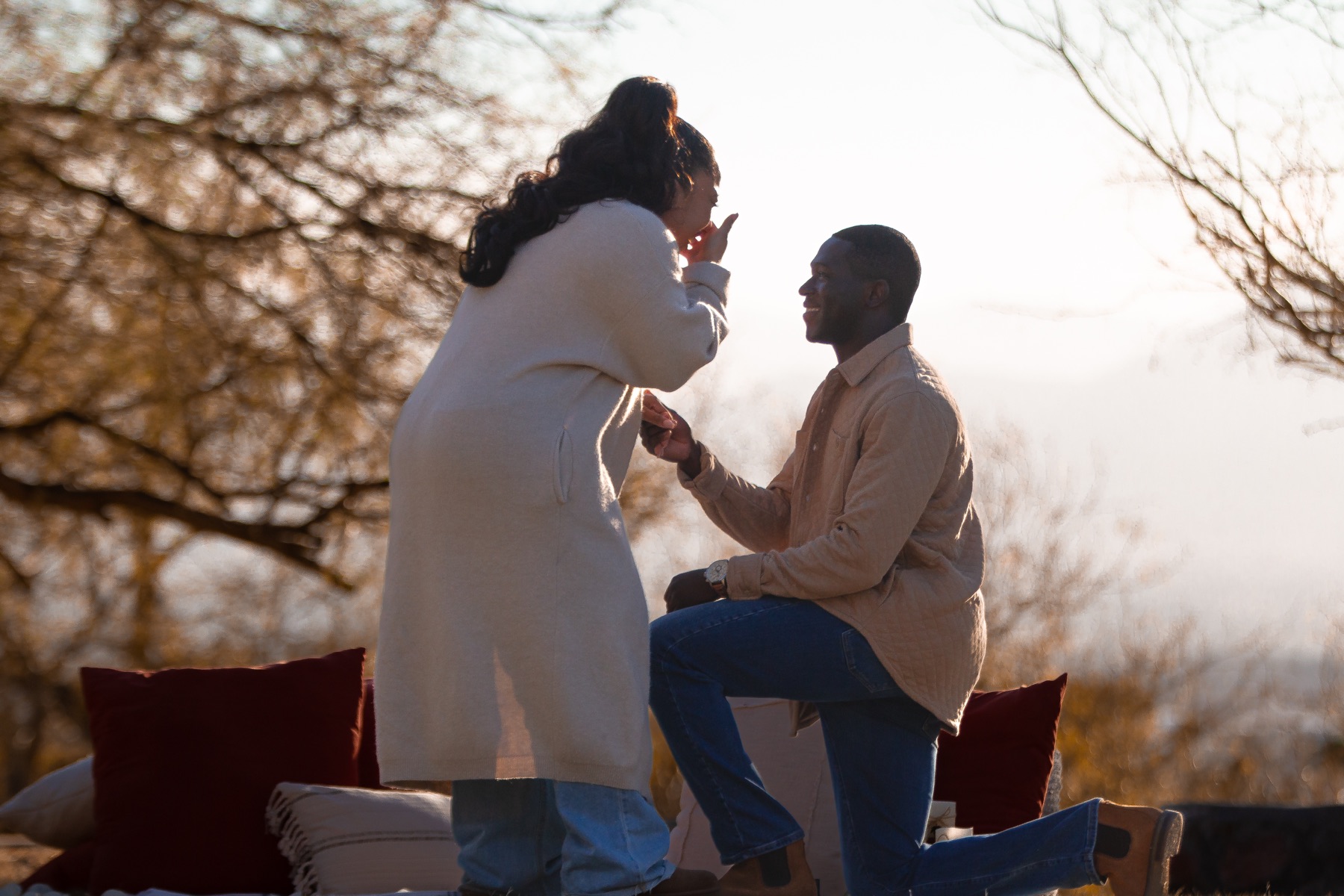 Ayo kneeling with a ring as Jordin reacts to his proposal